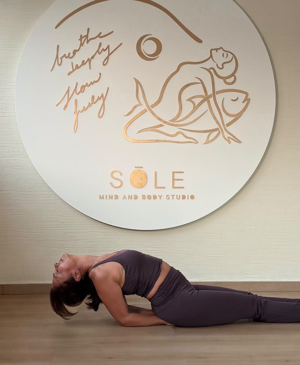 Fish pose on the studio floor beneath the SOLE sign